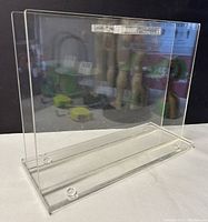 Clear acrylic bookcase viewed at an angle highlighting the transparent acrylic panels and base with feet.