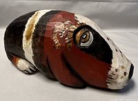 Side view of handcrafted wooden dog sculpture showing detailed paintwork and carved texture.