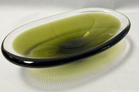 Angled side view of olive green oval Murano art glass bowl showing smooth glossy surface, dark rim, and conical base.