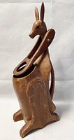 Front view of carved wooden kangaroo wine bottle carrier showing the upright kangaroo with hinged front legs holding the bottle slot.