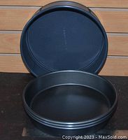 Four stacked 9-inch round cake pans showing black non-stick coating and metal construction.
