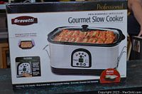 Front view of boxed Bravetti Professional Gourmet Slow Cooker showing product image, branding, features, and capacity details.