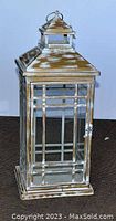 Front view of the large decorative lantern showing rectangular shape, glass panels, metal frame with distressed finish, and top handle.