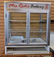Front view of bakery glass display cabinet with closed doors and visible shelves and storage rack underneath.