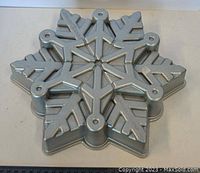Top view of the metal baking pan showing embossed snowflake and leaf pattern with circular holes at each tip