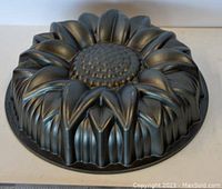 Photo of the baking pan's outer side showing the raised sunflower petal design and textured center in black coated metal.
