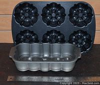 Two Nordic Ware bundt muffin pans with a ruler for scale on a dark surface