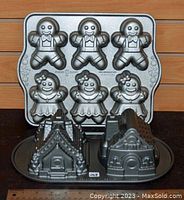 Photo of gingerbread men and women baking pan along with two gingerbread house pans on a wooden surface