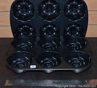 Two Nordic Ware mini Bundt pans placed upright, one black with classic fluted Bundt muffin molds, the other in lighter metal with rose design molds. A ruler shows size.