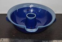 Blue glazed ceramic chicken roaster showing round dish and central cone for roasting chicken upright. Marked price sticker on rim.