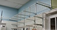 Multiple white wire shelves mounted on vertical wall standards with supporting brackets