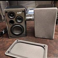 Pair of Moulsey branded bookshelf speakers; front view showing the drivers and one speaker with grill removed and laying on table