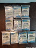 Ten packs of foil Mylar rescue blankets arranged in a group showing compact packaging.