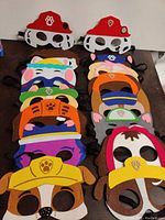 Full view of all 16 colorful felt Paw Patrol masks arranged in rows showing different character designs with hats and ears.