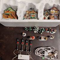 Overview of the 17-piece hand-painted winter village set including houses, lamp posts, figurines, trees, and power cord.