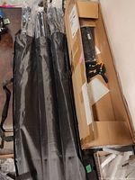 Full lot contents showing folded poles in black carrying bags next to long cardboard box containing clamps and other accessories.