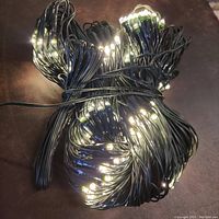 Photo of the fully coiled 300 white LED string lights with green wiring lit up to show the bulbs.