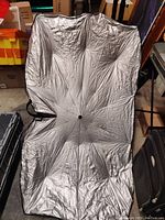 Front side of silver reflective umbrella style windshield sunshade spread flat to show full coverage surface area.