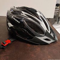 Side view of the Giant bicycle helmet showing the black and white design with ventilation holes and the brand logo.