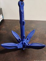 Blue metal folding boat anchor showing the four foldable flukes extended open.