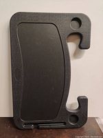 View of the top side of the black plastic steering wheel tray showing the large flat surface and hook areas for attachment.