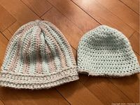 Front and side view of adult and child size pastel crochet hats on wooden floor
