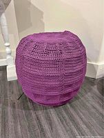 Side view of the purple crochet-style covered outdoor ottoman seat showing the crochet pattern and structure shape