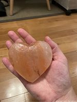 Rose quartz heart held in palm showing shape, size, and color variations.