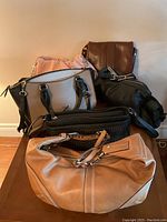 Overview photo showing six handbags of various styles and colors arranged on table.