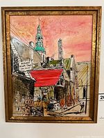 Full view of the framed French painting depicting a Quebec street scene with buildings, red awning, and copper tower dome under a pinkish sky.