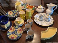 Wide view showing all ceramic items including floral plates, yellow cups, tea pot, and yellow ridged plates