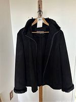 Front view of black jacket with faux fur trim on collar and cuffs, hanging on hanger