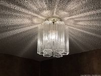 Fixture installed on textured popcorn ceiling, showing all six glass tubes and light emission pattern.