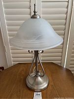 Front view of the lamp showing frosted glass dome shade and chrome metal base with decorative curved rods.