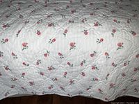Close-up of quilted coverlet showing pink rose pattern and quilt stitching