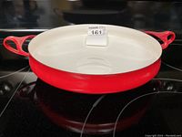 Top view of the red enamel paella pan showing white interior and two red loop handles