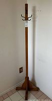 Full view of wooden standing coat rack showing its height and base structure.
