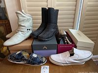 Overview of six shoes including two pairs of boots, slippers, slip-ons, shoe trees, and boxes.