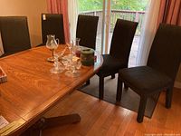 Set of five dark fabric covered dining chairs around a wooden dining table, showing overall style and condition.