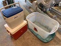 Photo showing both coolers stacked with storage bin next to them on concrete floor.