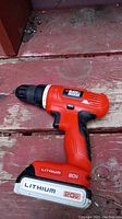 Black & Decker 20V orange lithium cordless drill on red wooden floor