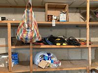Wide view of three wooden shelves with electrical cords, bags, and light bulb boxes