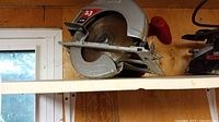 Skill saw on shelf showing whole unit with blade and red handle