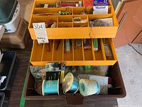Top view of two tackle boxes showing spools of fishing line and some packaged lures in yellow compartmentalized tray.
