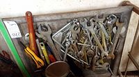 Tray of mixed wrenches and hand tools viewed from above showing various sizes and types with some rust and wear