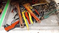 Overview of various used hand tools including pipe wrenches, pliers, and cutters in a box