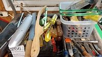 Photo showing various screwdrivers, a wooden drawknife, and other hand tools in a container.