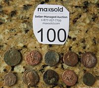 Top view showing all 10 Roman bronze coins laid out on a granite surface with lot number tag.