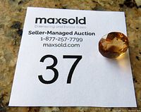 Round-shaped faceted citrine gemstone shown on auction lot card with number 37, displaying color and cut.