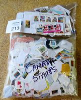 Full view of one labeled bag containing many Canadian postage stamps on torn paper fragments